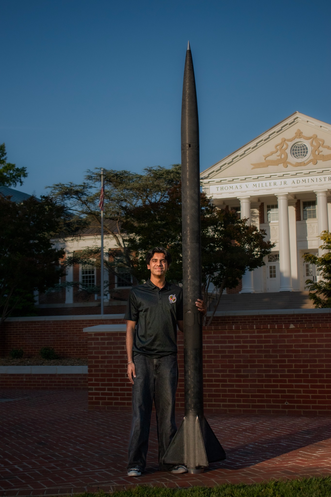 Subhan standing beside a rocket on the University of Maryland campus