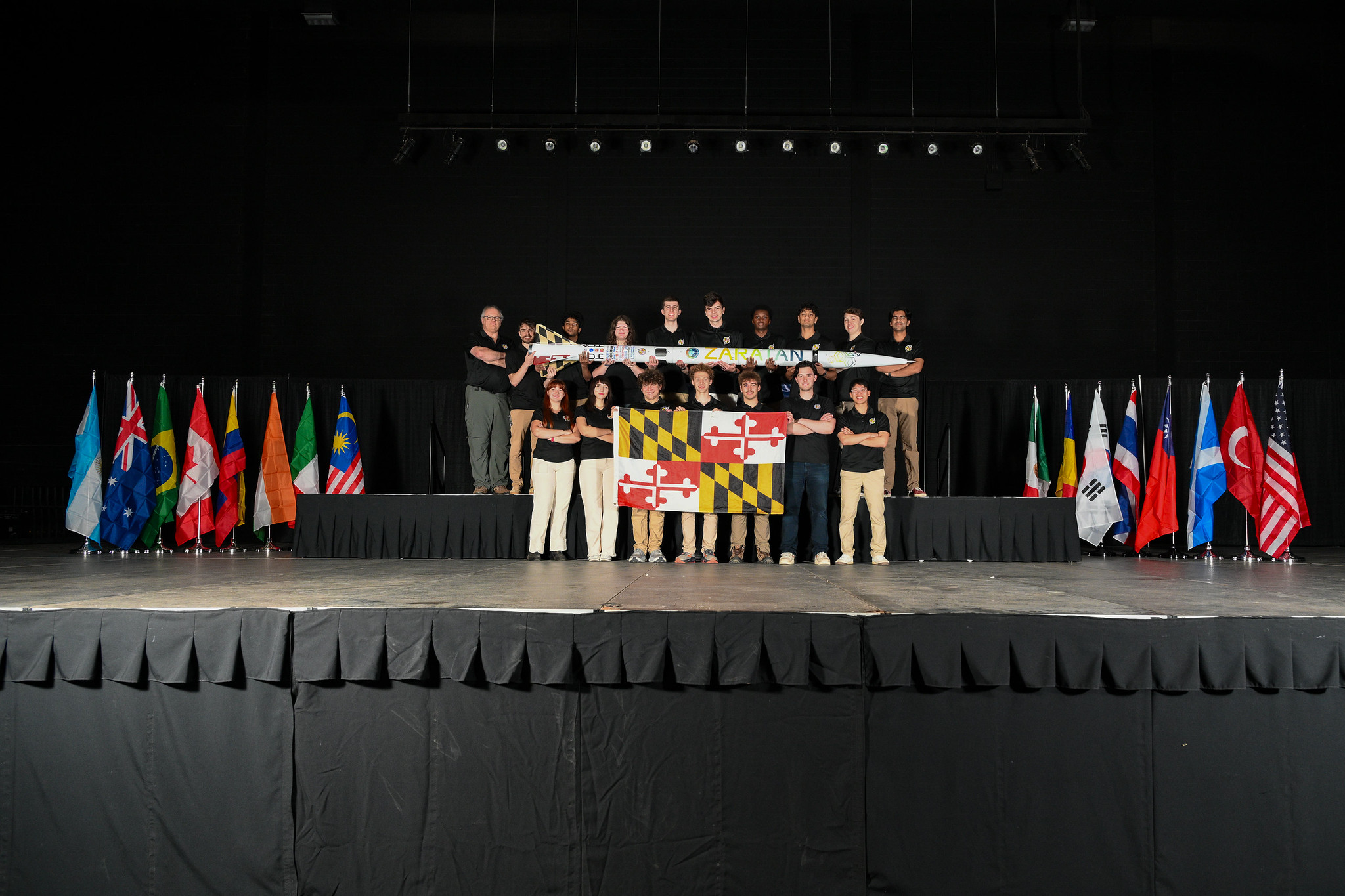 Terrapin Rocket Team on stage with their rocket and the Maryland flag